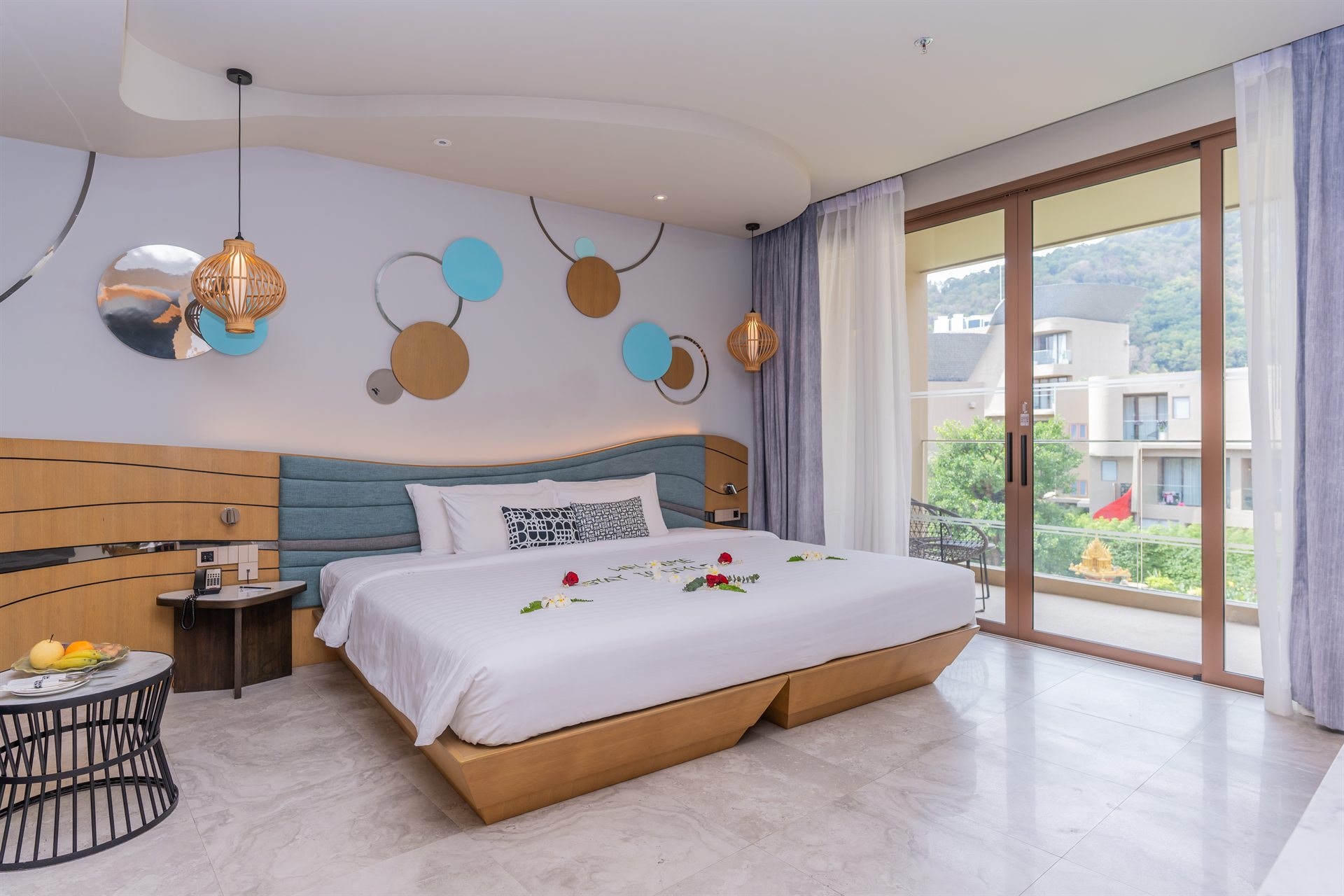 Modern Room Design at Metadee Concept Hotel Phuket Bright guest room with a large bed, circular wall decorations and glass doors opening to a terrace at Metadee Concept Hotel