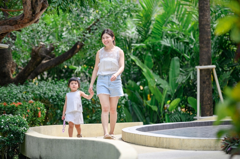 Parent and child walking through tropical resort gardens Parent and child walking through tropical resort gardens