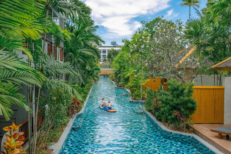Parent and child floating in a tropical resort pool