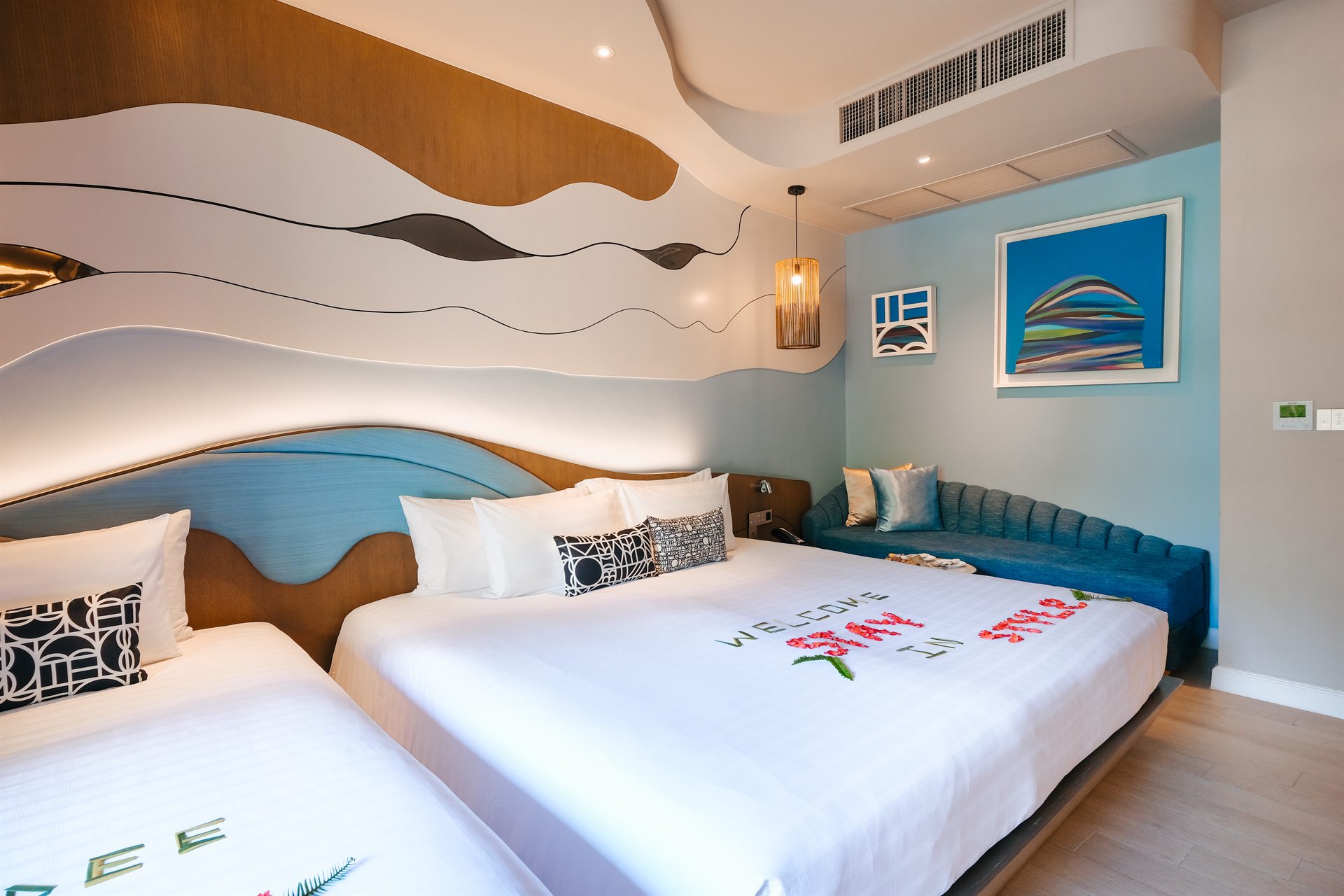 Space to Unwind on a Family Holiday in Phuket Spacious guest room with beds, a blue sofa and contemporary decor at Metadee Phuket