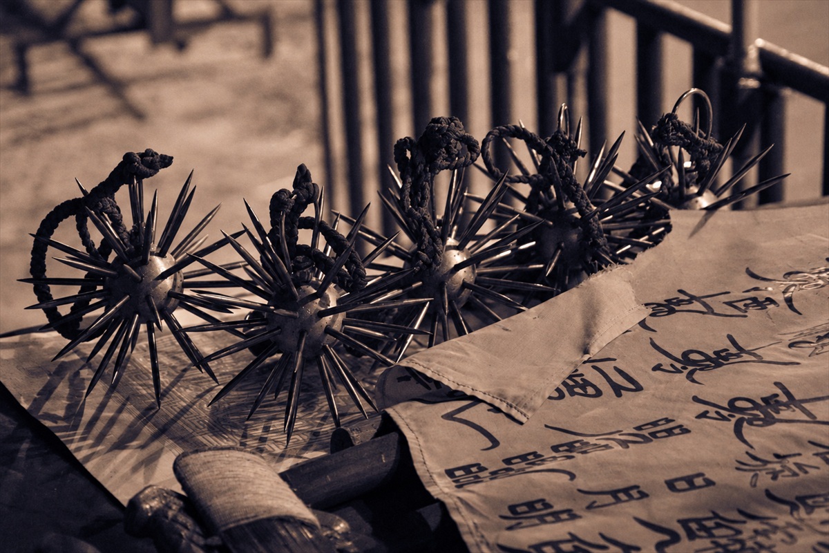 Traditional spiked ceremonial objects displayed on cloth in a sepia-toned photograph