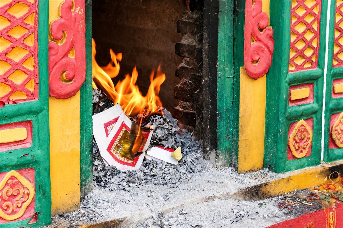 Ritual paper offerings burning in a colourful Chinese shrine furnace in Phuket