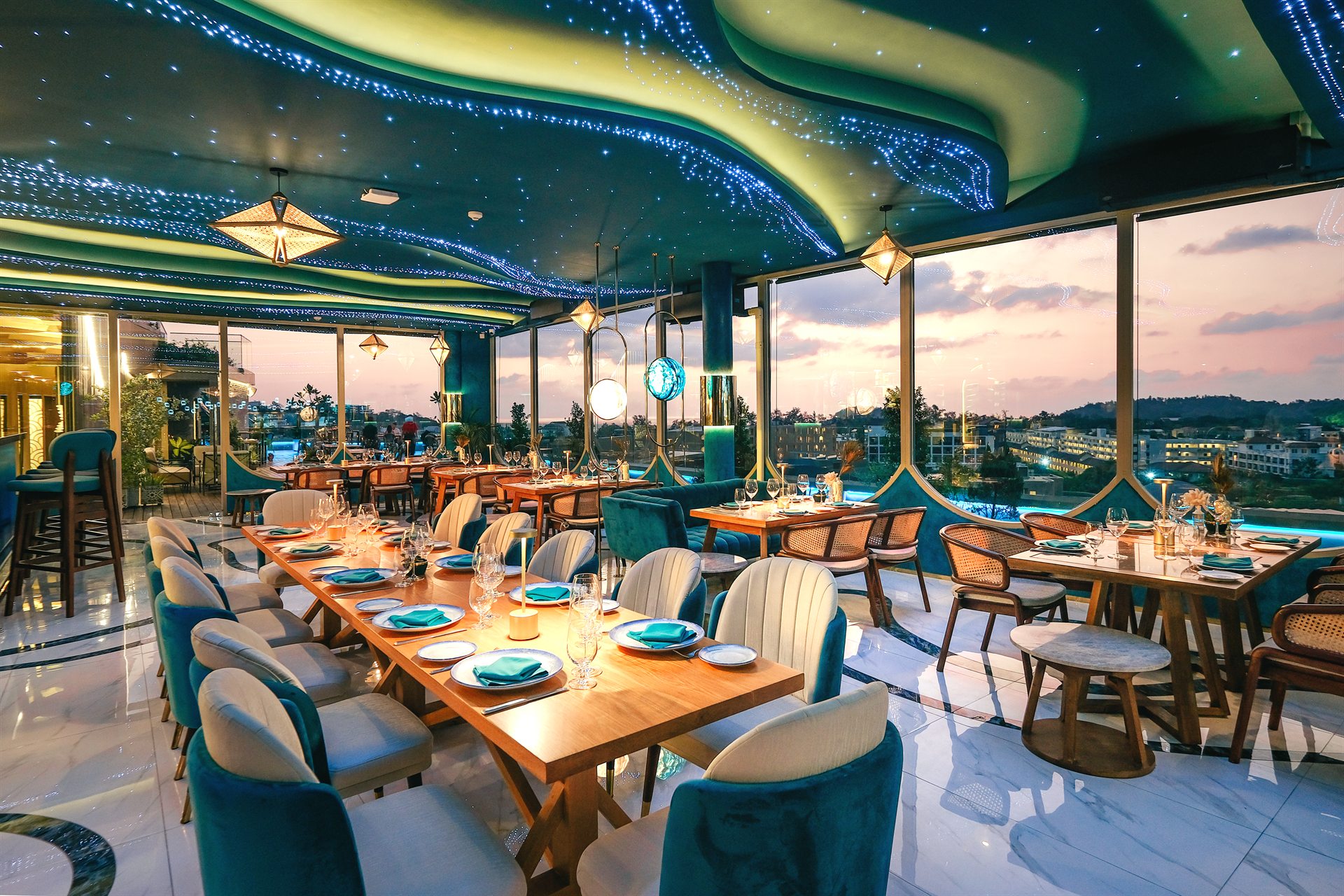 Sunset Atmosphere at Moon Terrace Rooftop Phuket Moon Terrace rooftop restaurant with teal seating and panoramic windows at sunset